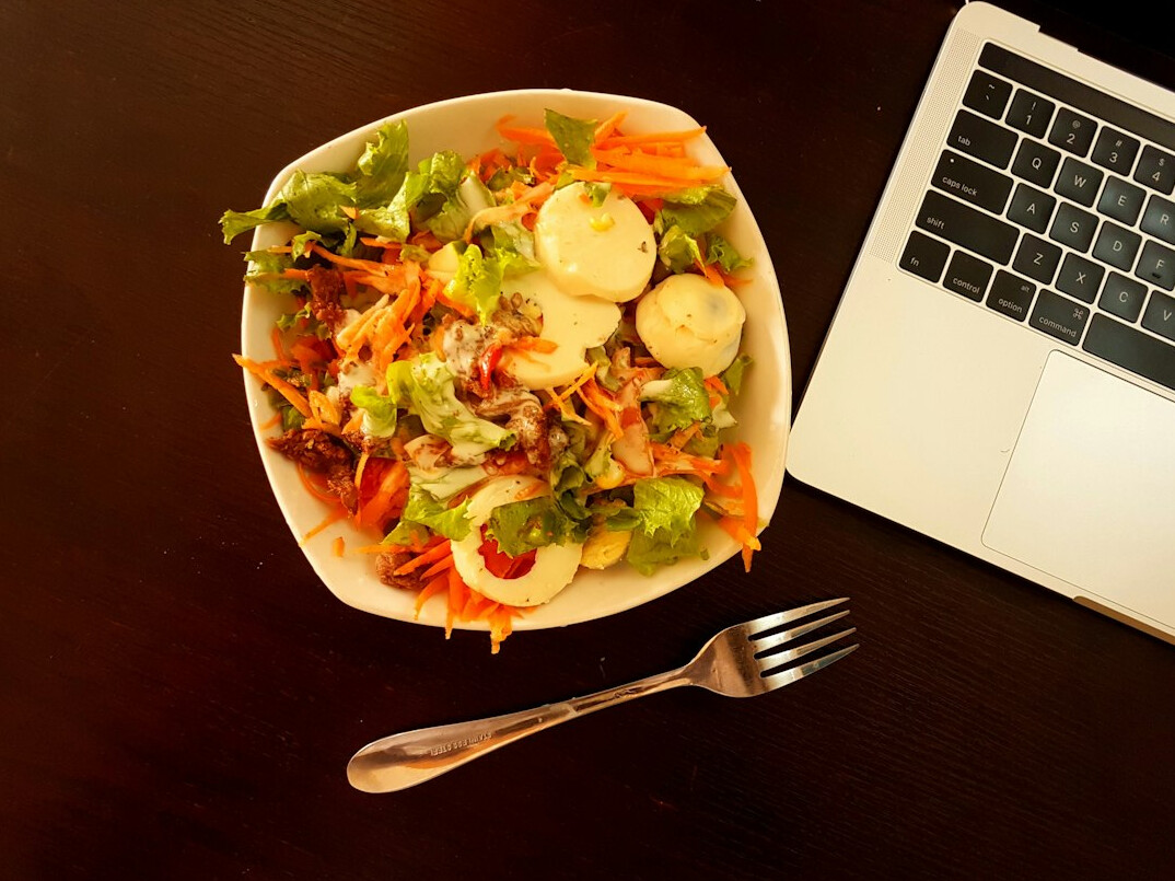 Laptop on a desk with a notebook and coffee